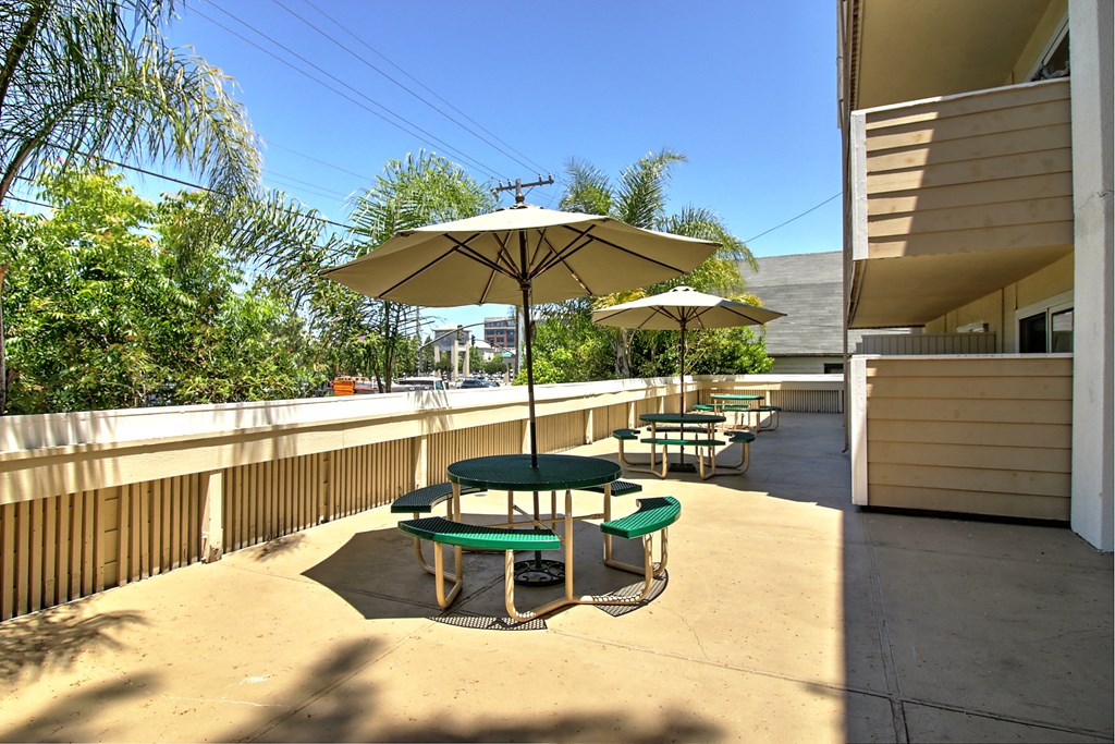 A sunny day at a patio with a green table and chairs.