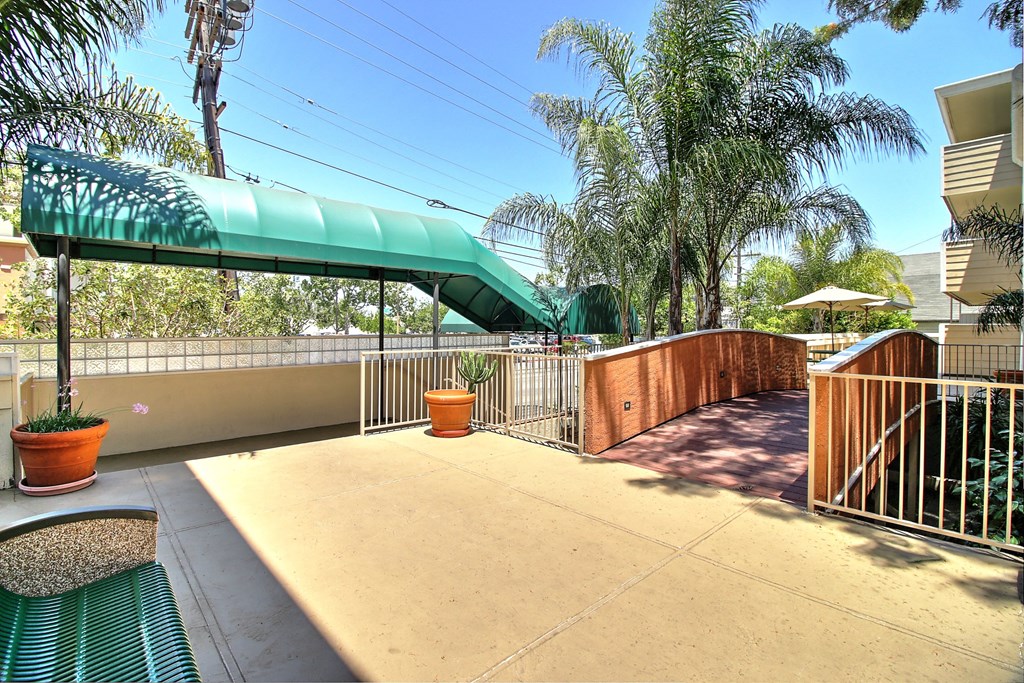 A patio with a green awning and a bench.