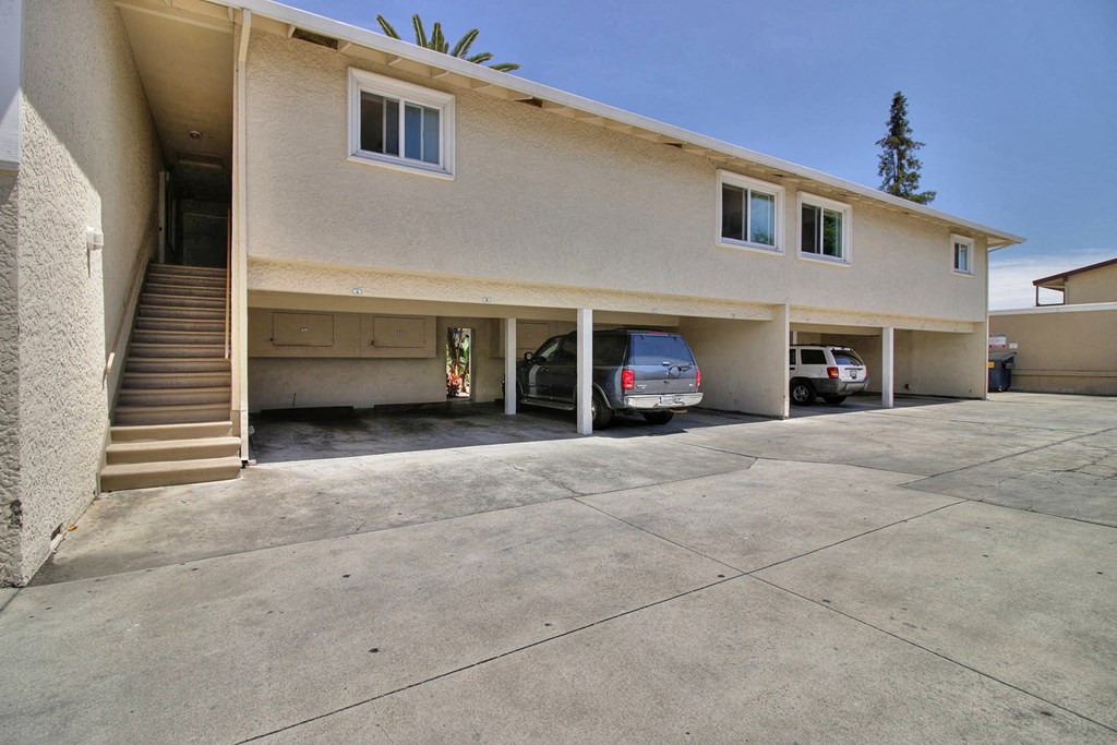 a beige apartment building with cars parked in the driveway