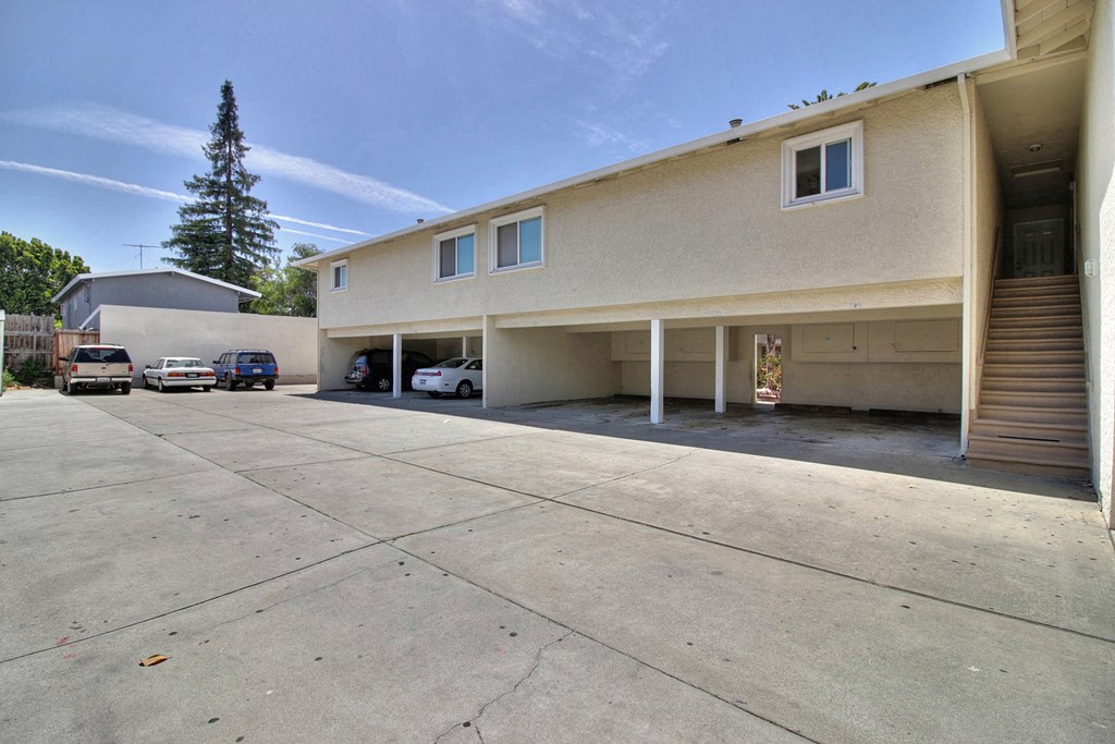 an empty parking lot in front of a tan building with cars parked