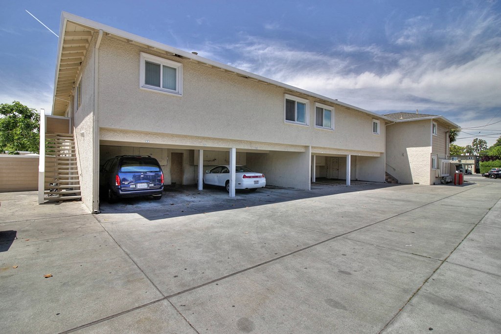 a beige building with two cars parked in front of it