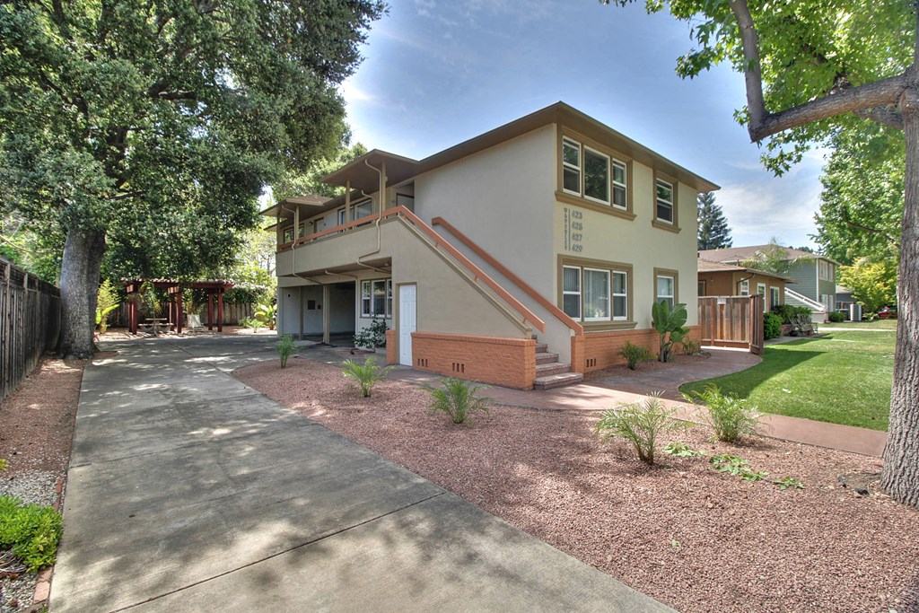 the front of a house with a driveway and trees