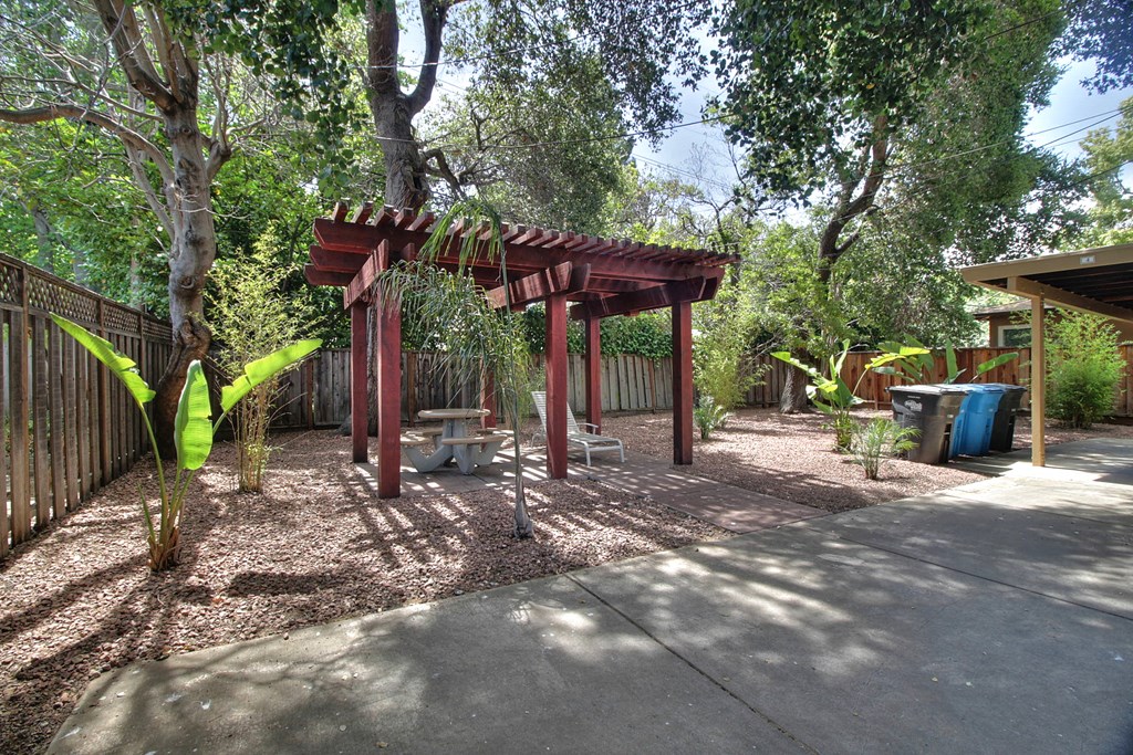 a picnic area in a backyard with a wooden structure