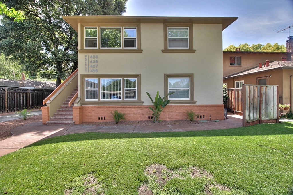 the front of a house with a yard and a staircase