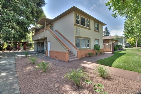 A house with a brown and beige exterior and a red staircase.