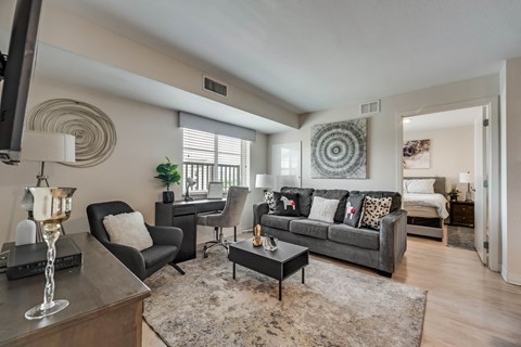 A living room with a grey couch and a black chair.