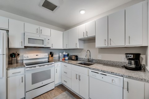 A kitchen with white appliances and cabinets.