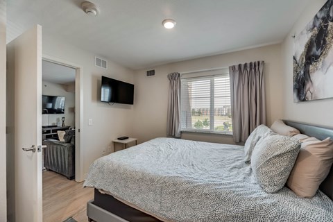 A bedroom with a large bed and a flat screen TV mounted on the wall.