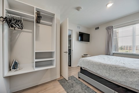 A bedroom with a bed, a wardrobe, and a television.
