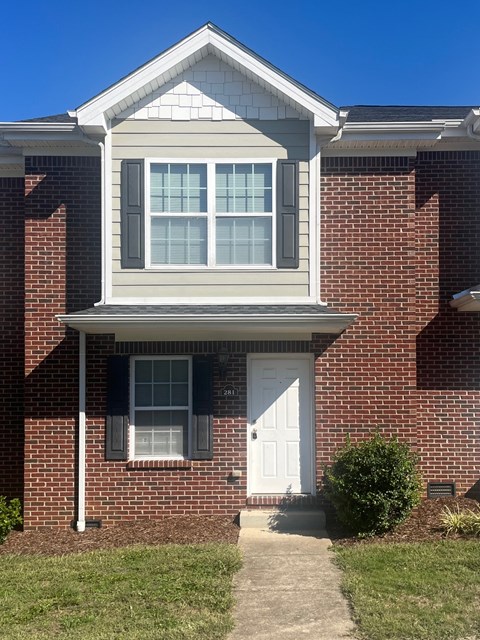 A house with a white door and a window with white blinds.