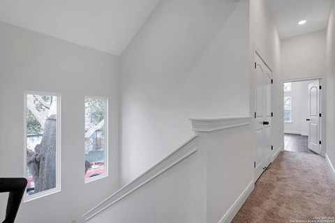 A long hallway with white walls and a carpeted floor.