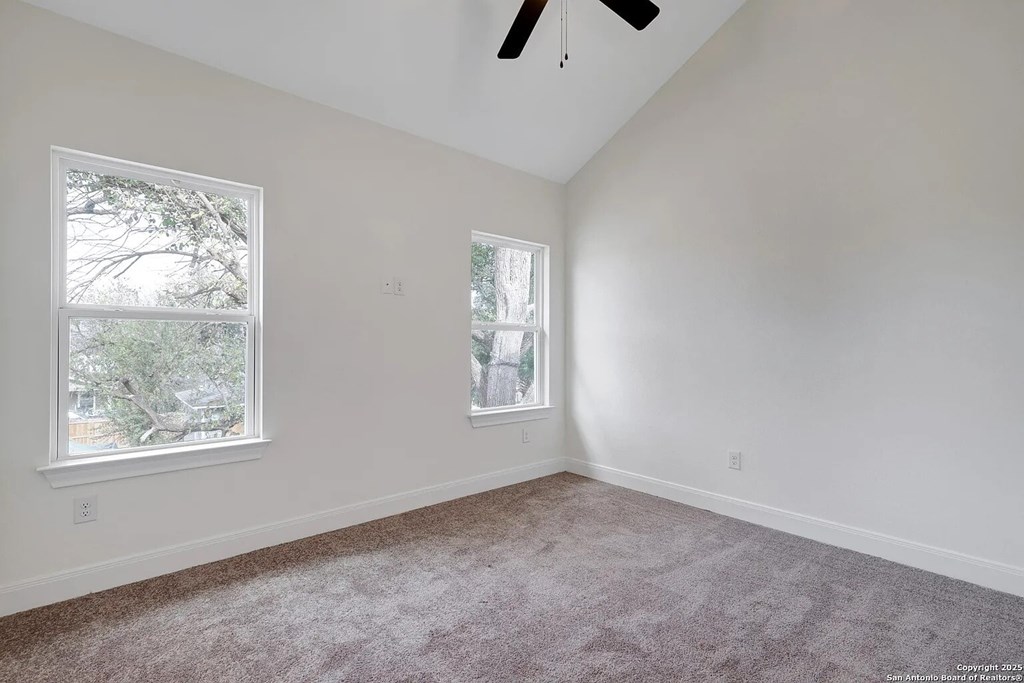 A room with a ceiling fan and two windows.