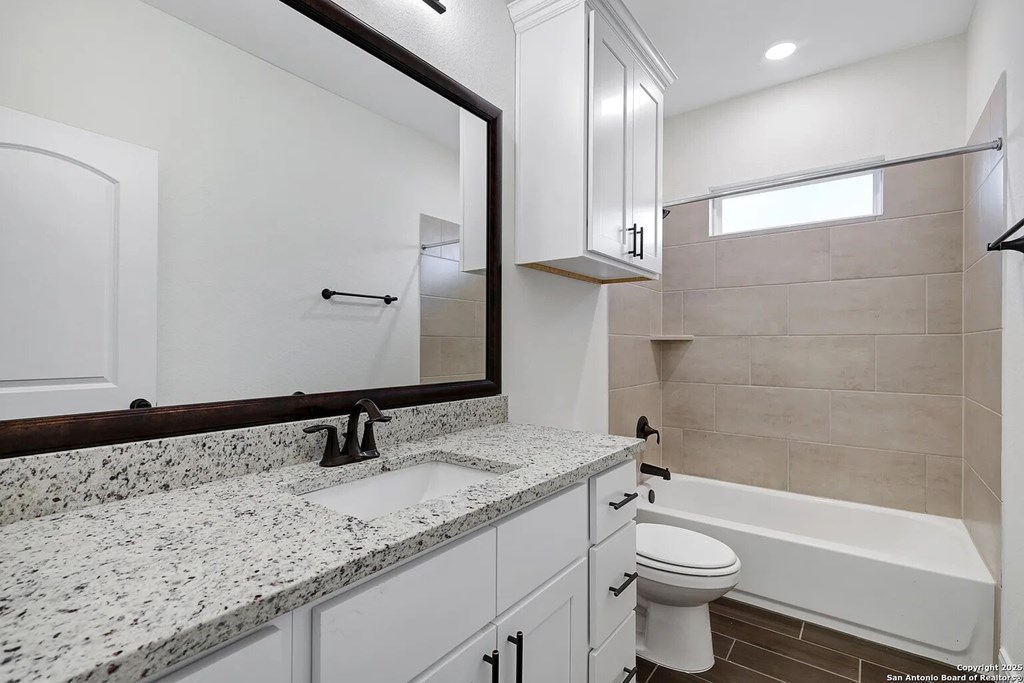 A white bathroom with a marble counter top and a white toilet.