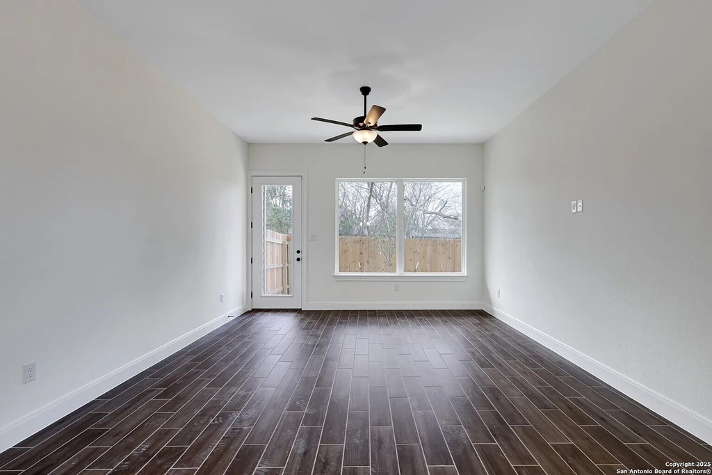 A room with a ceiling fan and wood flooring.
