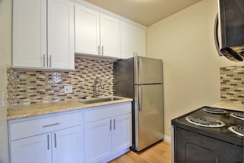 a kitchen with white cabinets and a stainless steel refrigerator