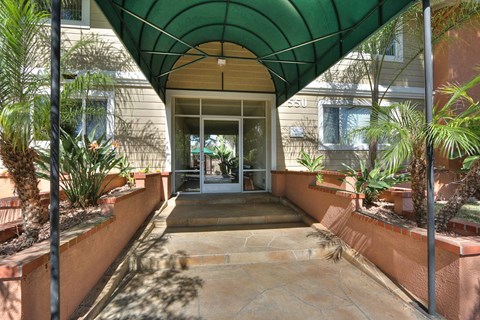 A covered walkway with a green canopy and a stone floor.