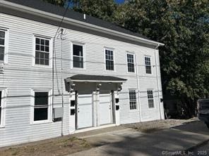 A white building with a covered entrance and a car parked in front.