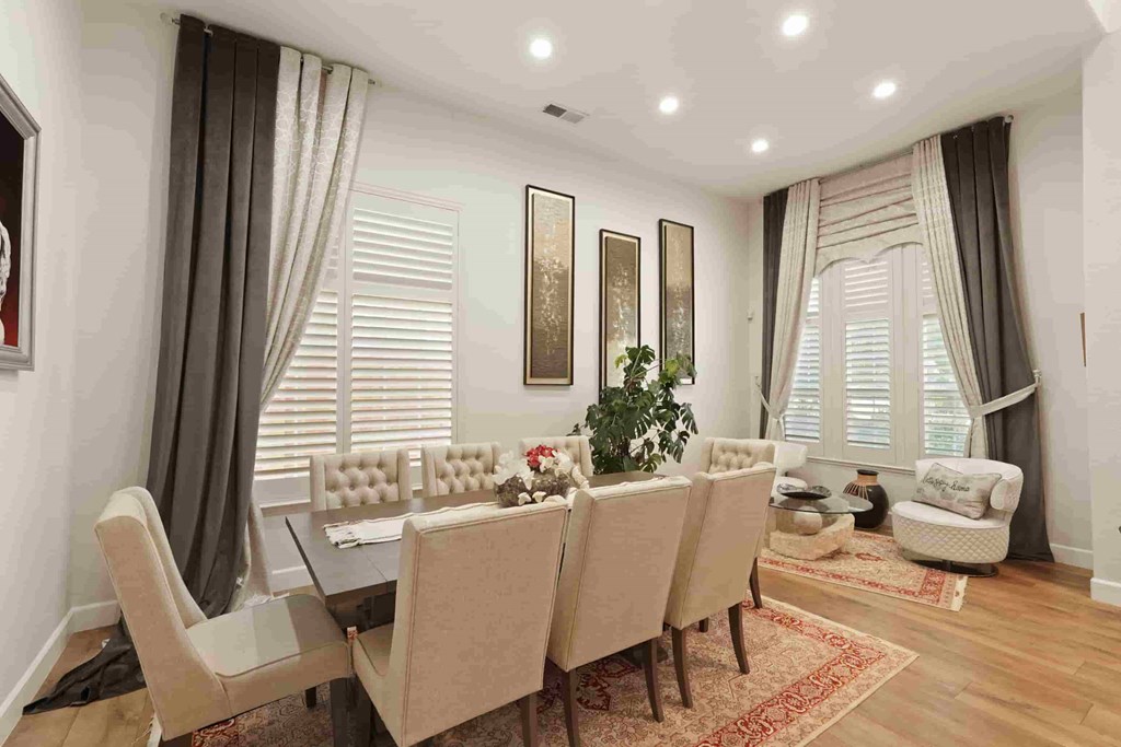 A dining room with a table set for six with chairs around it.