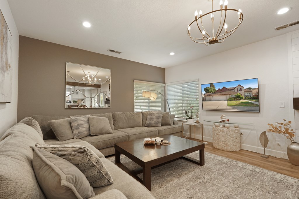 A living room with a grey couch, a coffee table, and a painting on the wall.