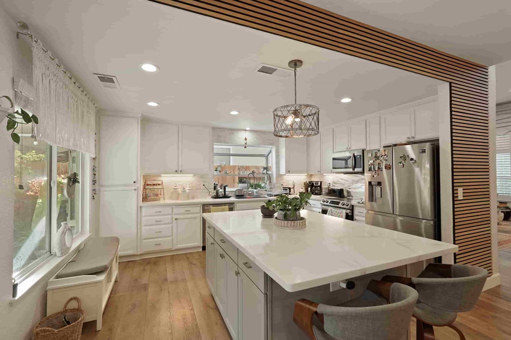 A modern kitchen with a large island and a window with curtains.