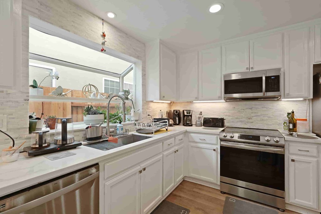 A kitchen with white cabinets and a stainless steel oven.