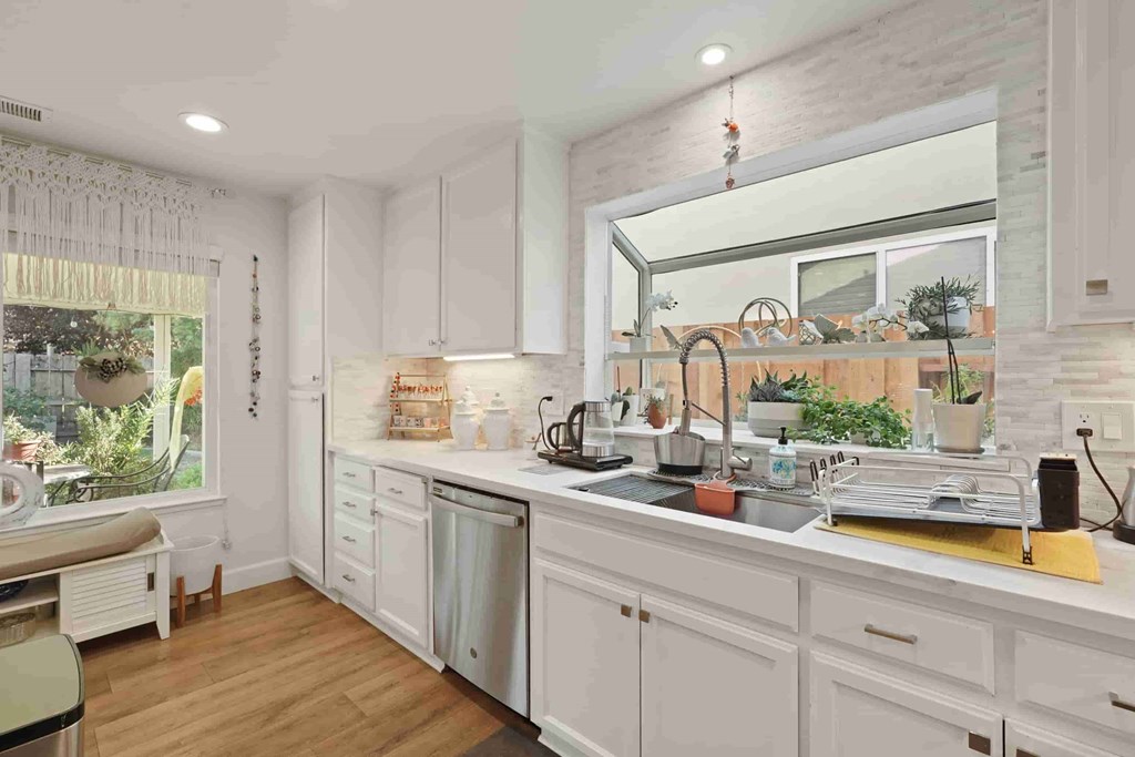 A kitchen with white cabinets and a wooden floor.