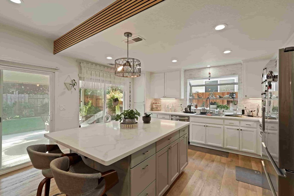 A kitchen with a large island and a view of a backyard.