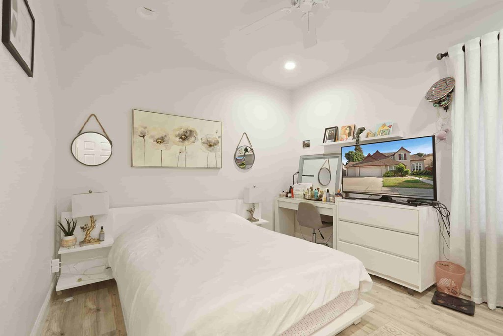 A bedroom with a bed, desk, and television.