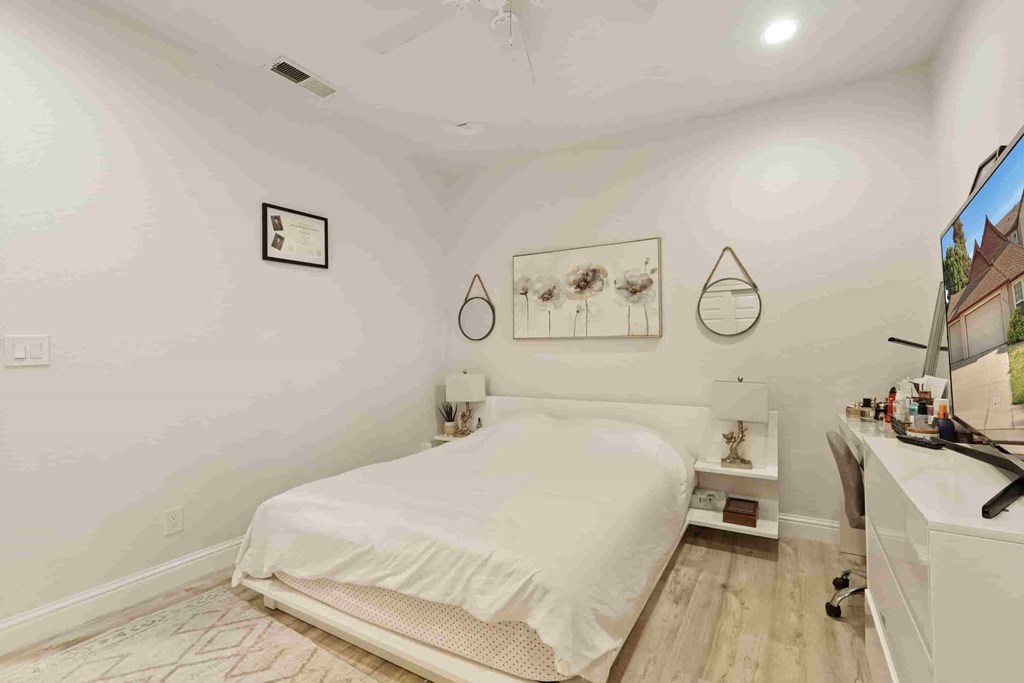 A bedroom with a bed, nightstand, and a mirror on the wall.