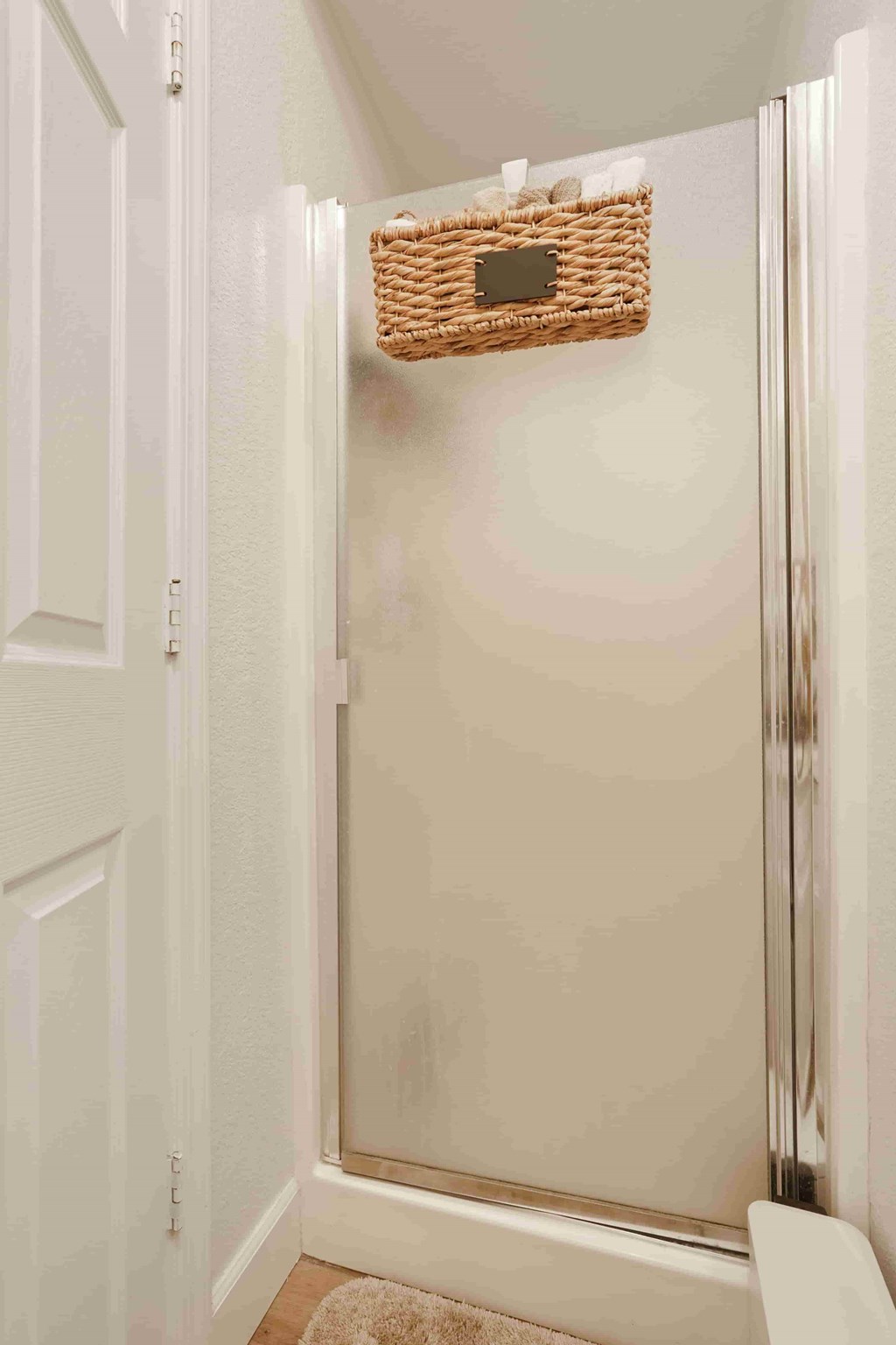 A white door with a basket hanging on the wall.