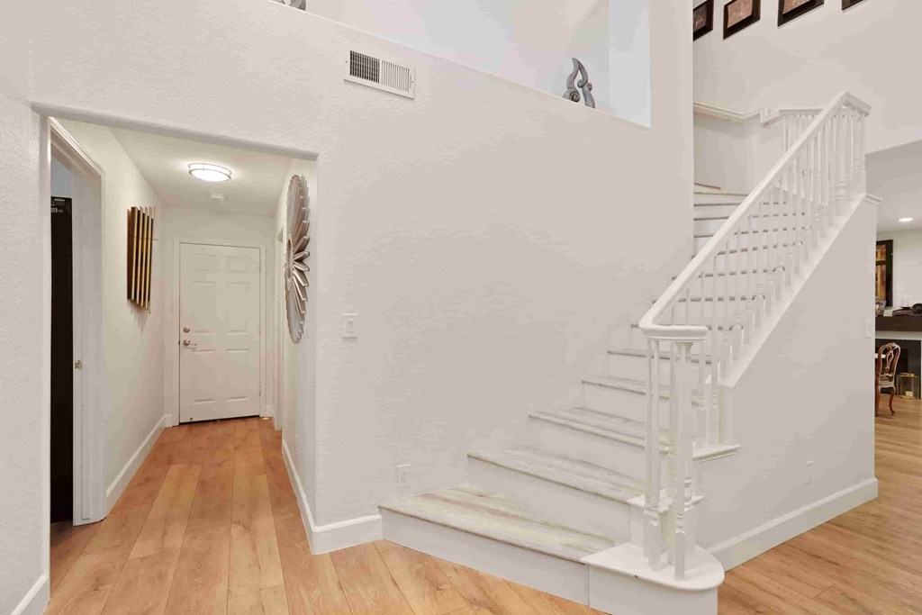 A white staircase with a wooden handrail and steps.