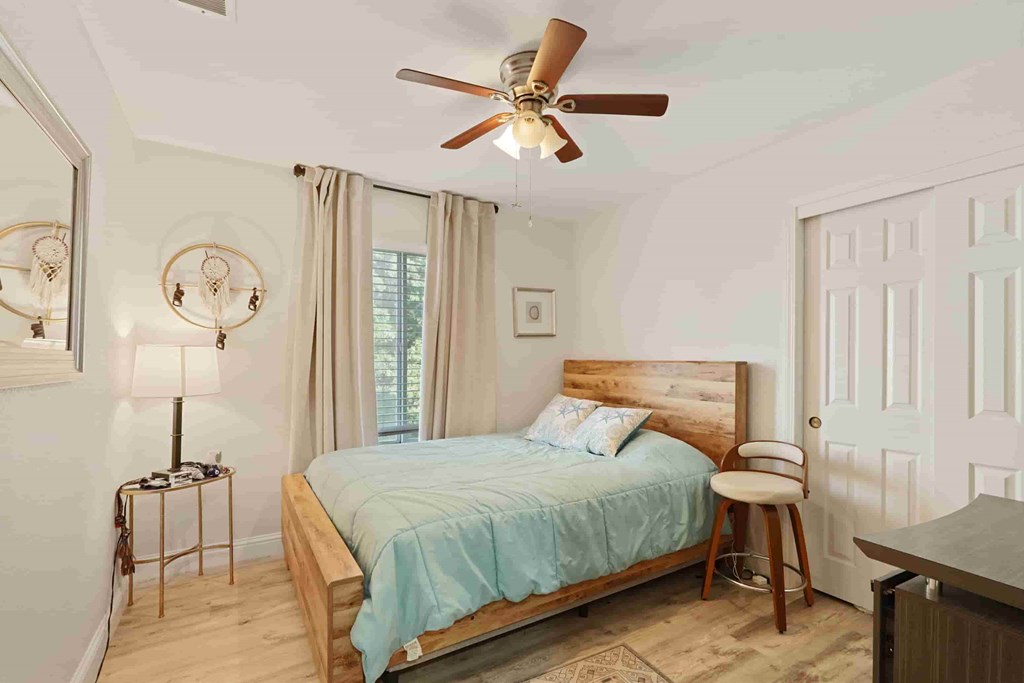 A bedroom with a bed, a chair, and a ceiling fan.