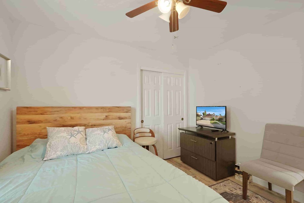 A bedroom with a bed, a chair, and a television.