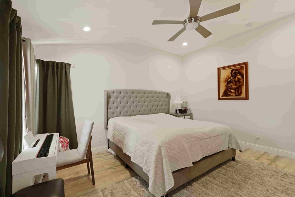 A bedroom with a bed, chair, and a piano.