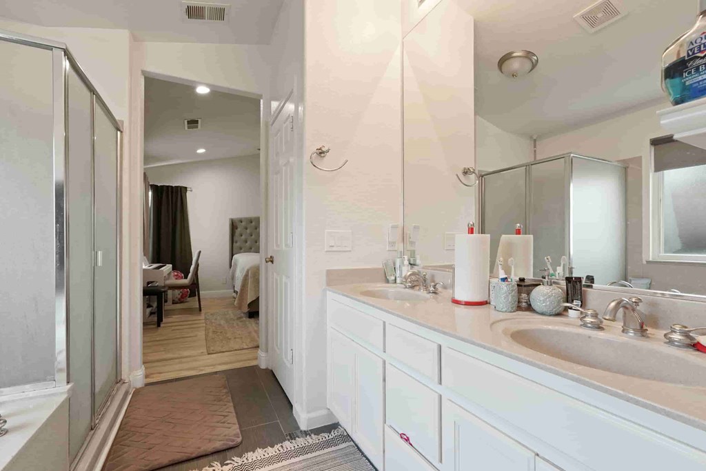 A bathroom with a sink, mirror, and a glass shower door.