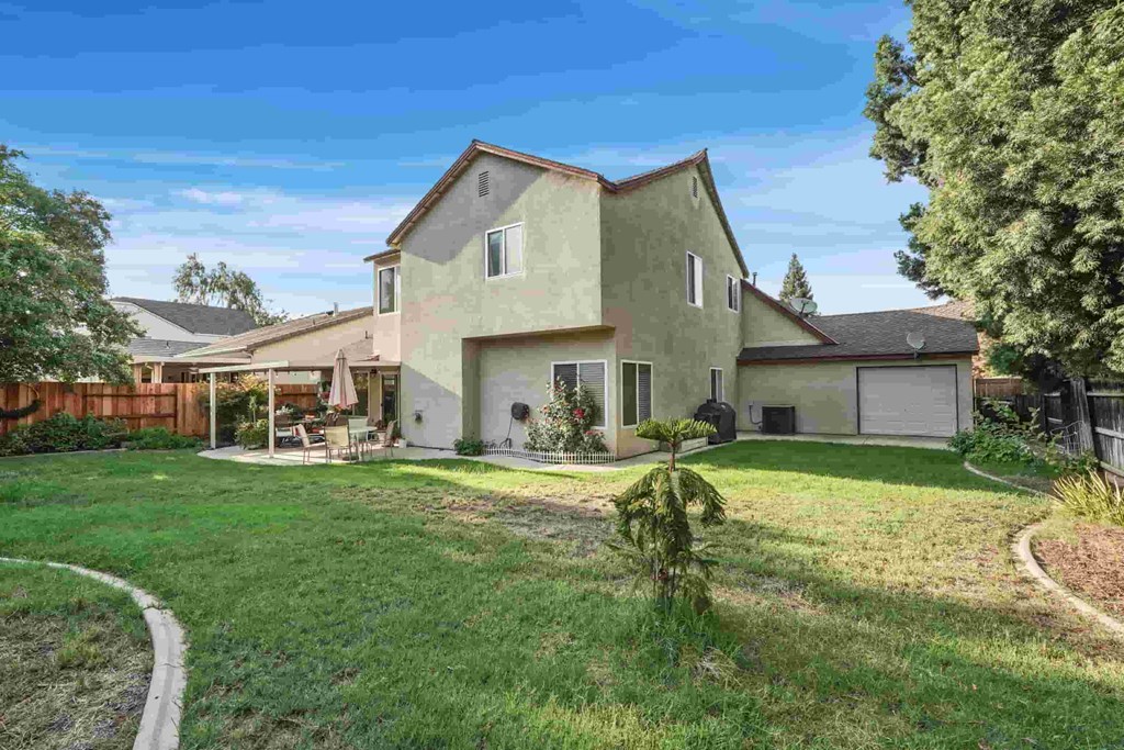 A house with a green lawn and a small tree in front.