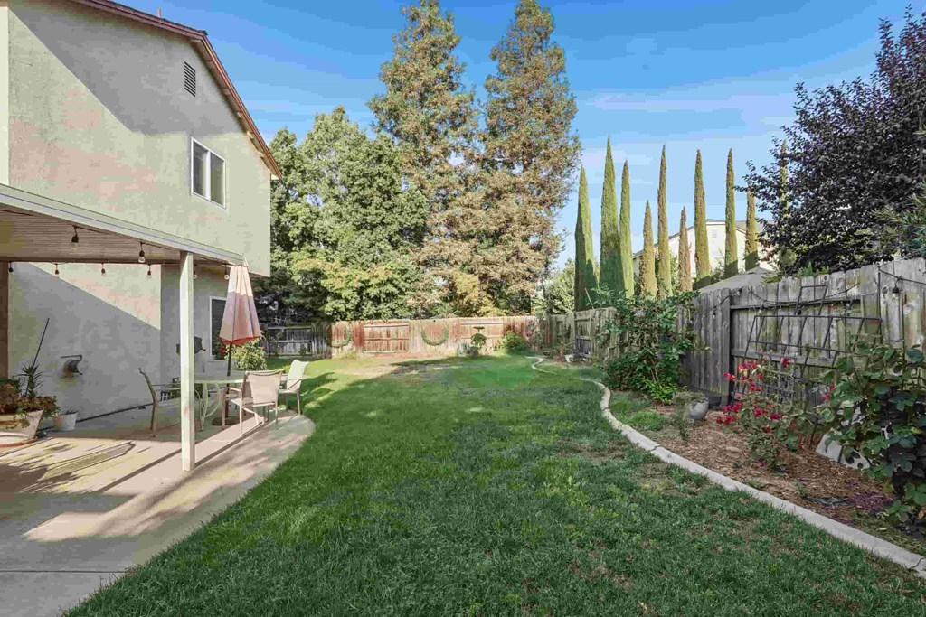 A backyard with a green lawn and a fence.