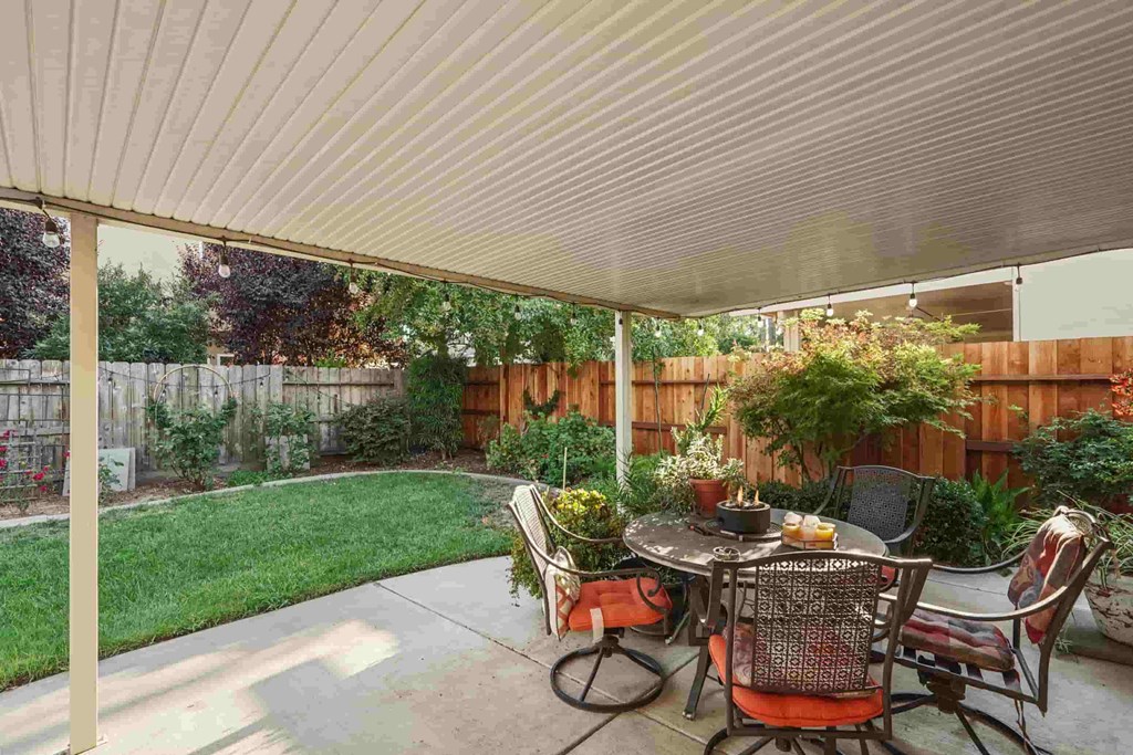 A patio with a table and chairs under a roof.