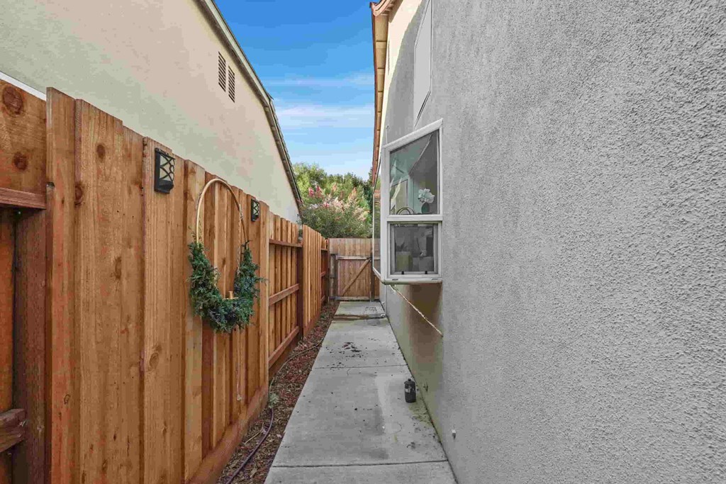 A narrow alley with a wooden fence on one side and a white wall on the other.