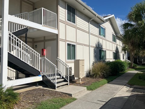 A white building with a red fire alarm box on the staircase.