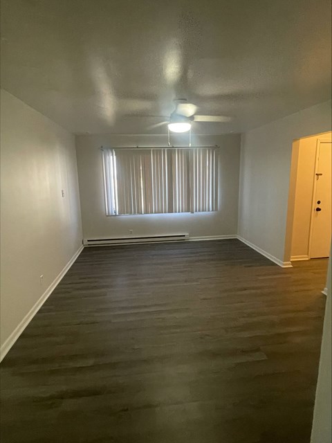 A room with wooden floors and a window with blinds.