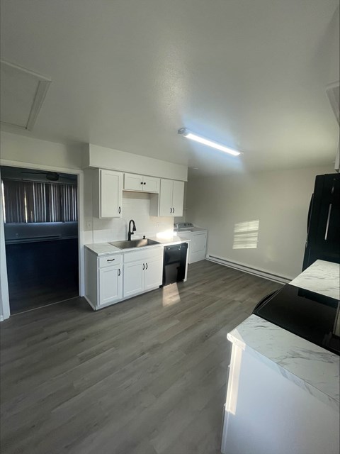 A kitchen with white cabinets and a black countertop.