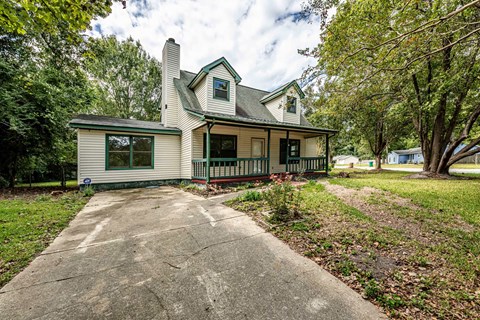 A house with a green lawn and trees in the background.