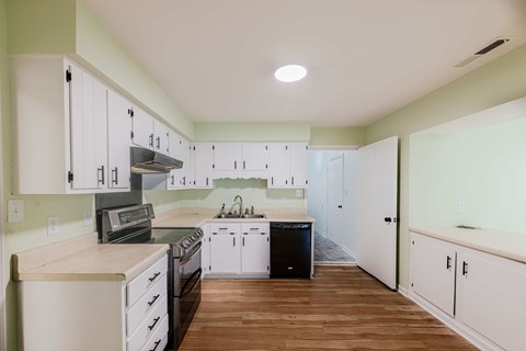 A kitchen with white cabinets and a wooden floor.