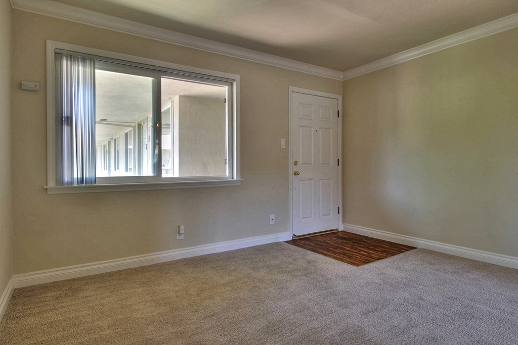 an empty living room with a window and a door