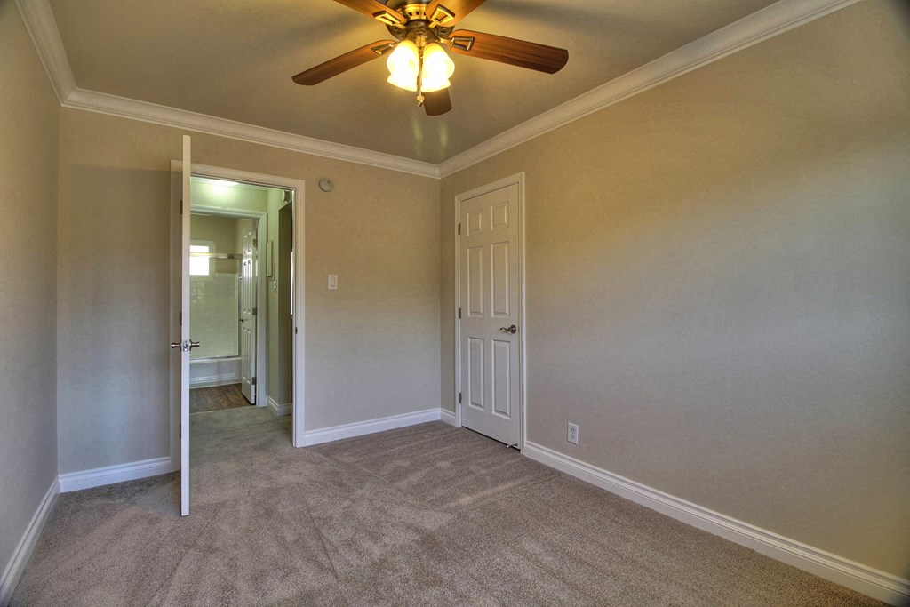 a bedroom with a ceiling fan and a door to a hallway