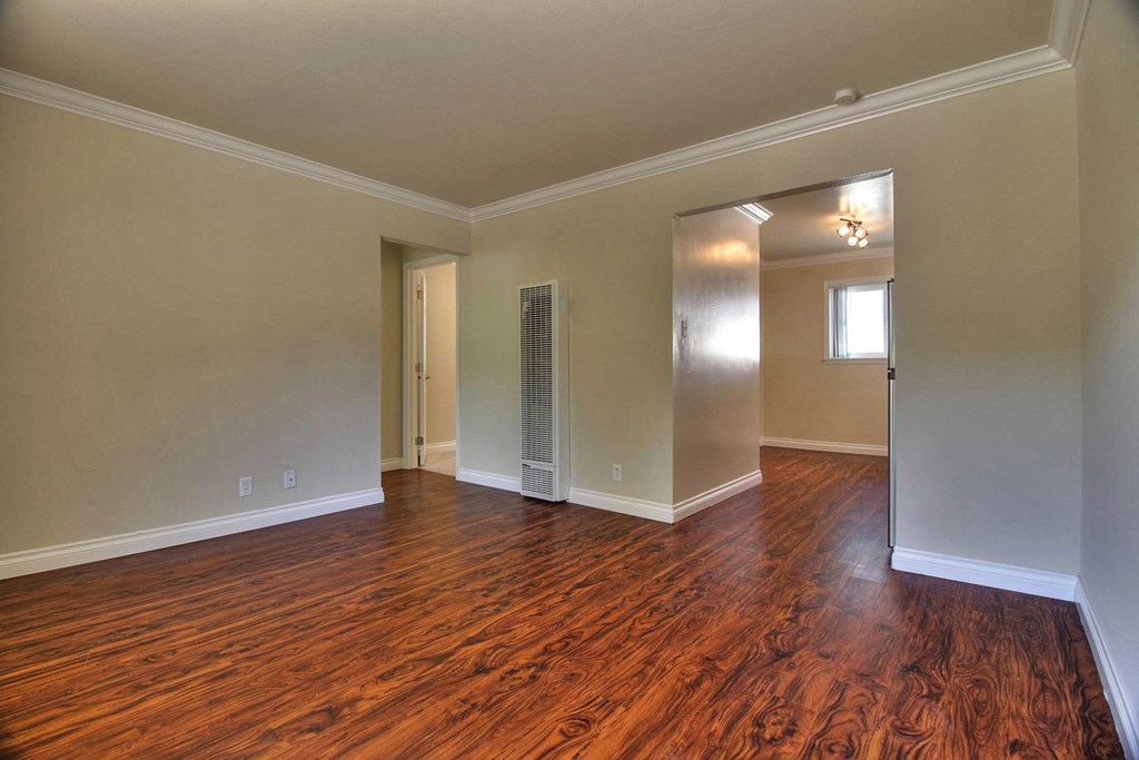an empty living room with wood flooring and a closet