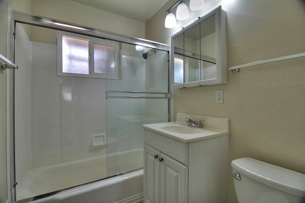 a bathroom with a shower sink and mirror and a toilet