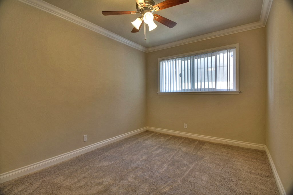 an empty living room with a ceiling fan and a window