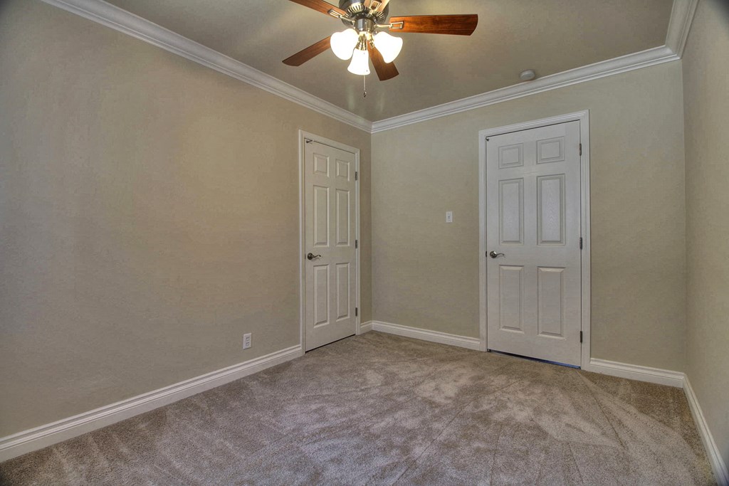 a bedroom with two doors and a ceiling fan